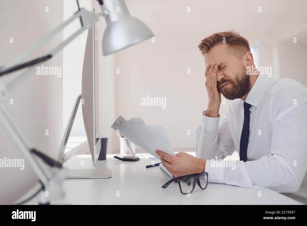 Beaucoup de travail au bureau. Un homme d'affaires fatigué et occupé travaille avec l'ordinateur. Banque D'Images