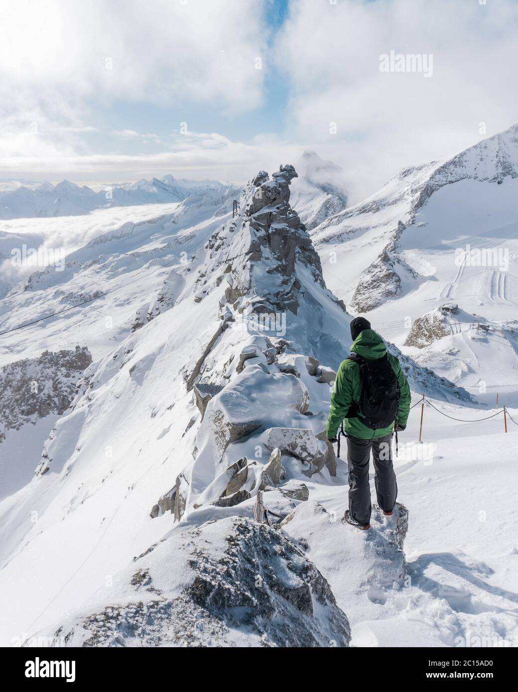 Le voyageur contemple un paysage de montagne enneigé. L'homme reste au-dessus de la brume intense dans la vallée profonde. La randonnée dans la nature pure est l'activité de loisirs populaire Banque D'Images