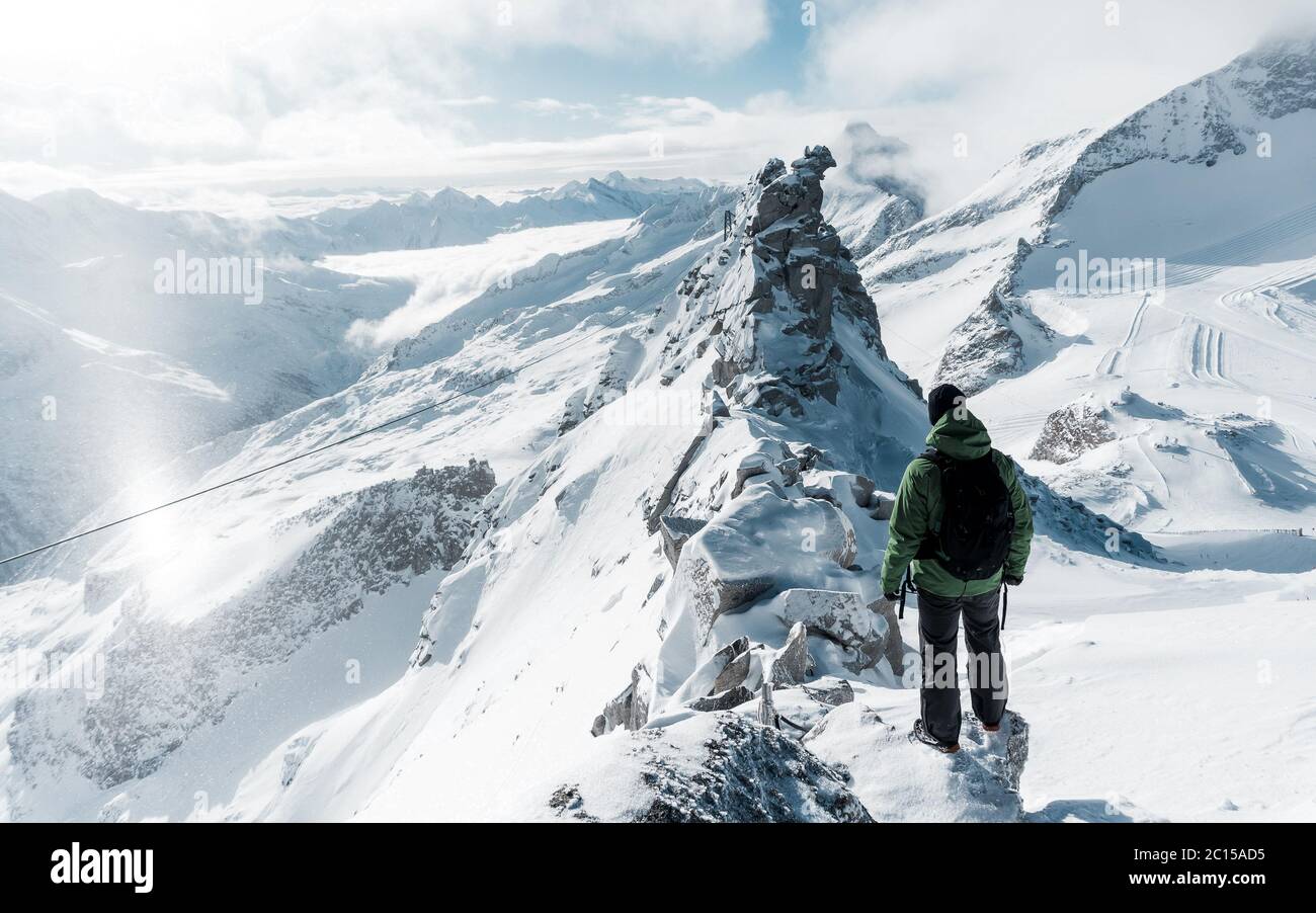 Le voyageur contemple un paysage de montagne enneigé. L'homme reste au-dessus de la brume intense dans la vallée profonde. La randonnée dans la nature pure est l'activité de loisirs populaire Banque D'Images