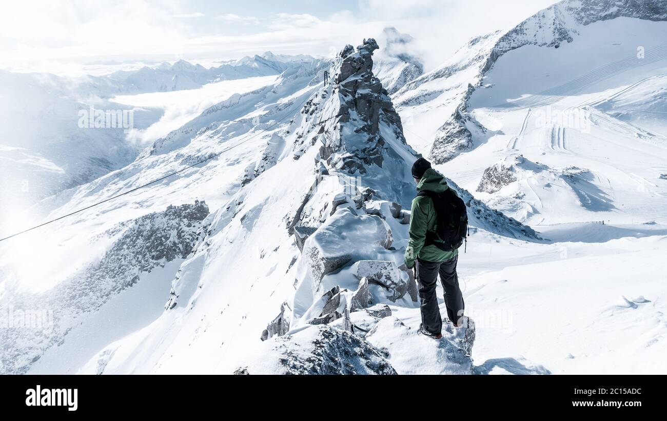 Le voyageur contemple un paysage de montagne enneigé. L'homme reste au-dessus de la brume intense dans la vallée profonde. La randonnée dans la nature pure est l'activité de loisirs populaire Banque D'Images