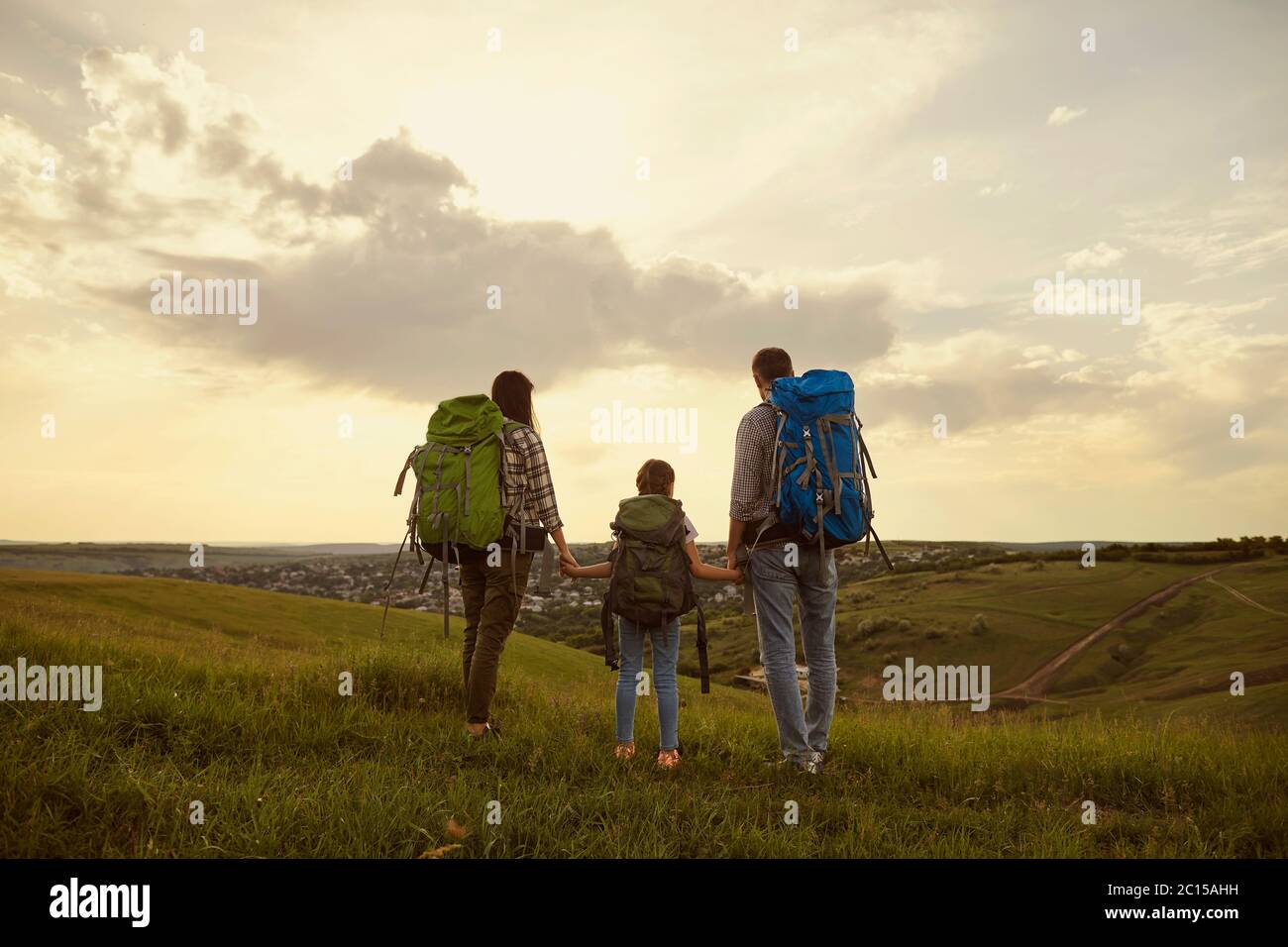 Famille avec sacs à dos. Touristes debout dans la nature randonnée le soir. Vue arrière. Banque D'Images