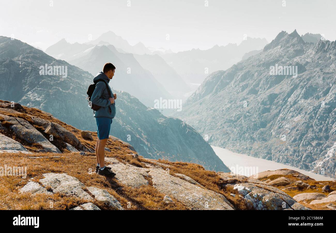 Un alpiniste au sommet d'un rocher et regardant le paysage alpin de montagne d'été. Randonneur ou grimpeur sur une ascension aventure jusqu'au sommet Banque D'Images