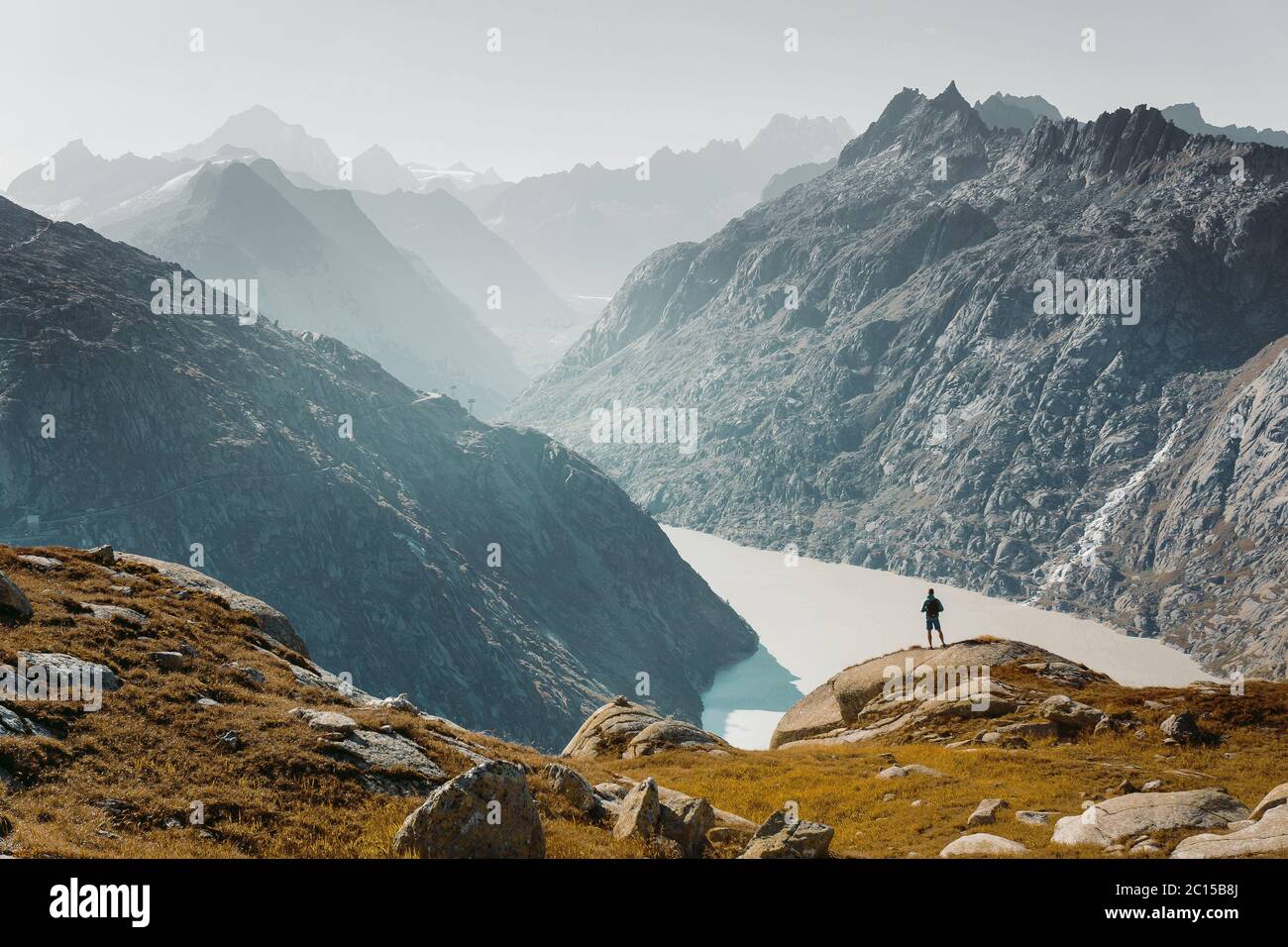 Un alpiniste au sommet d'un rocher et regardant le paysage alpin de montagne d'été. Randonneur ou grimpeur sur une ascension aventure jusqu'au sommet Banque D'Images