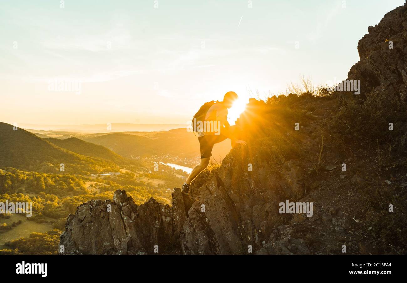 Voyagez seul avec un homme touristique sur les montagnes de la falaise et en regardant la vallée. Silhouette de la personne sur le rocher au coucher du soleil. Randonnée Banque D'Images
