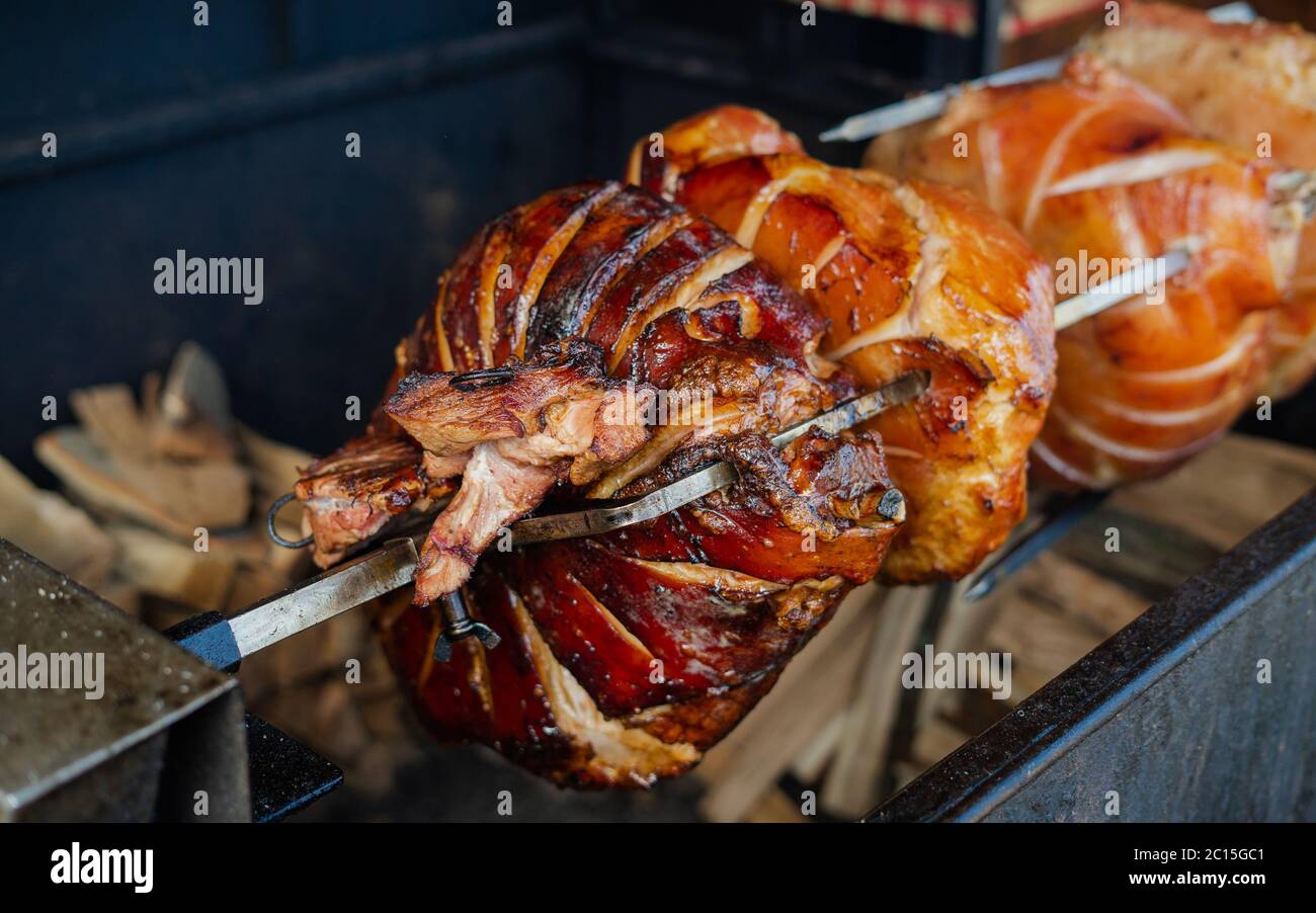 Gros plan de la cuisson de gros morceaux de viande sur une broche d'un  barbecue de rue. Le jambon de porc grillé sur une cheminée est un célèbre  plat traditionnel de cuisin