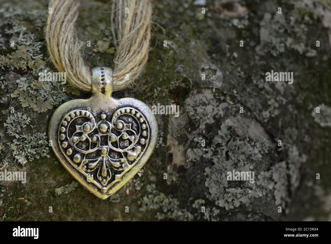 Collier bavarois traditionnel en fibres de jute et coeur devant un vieux tronc d'arbre avec lichen Banque D'Images