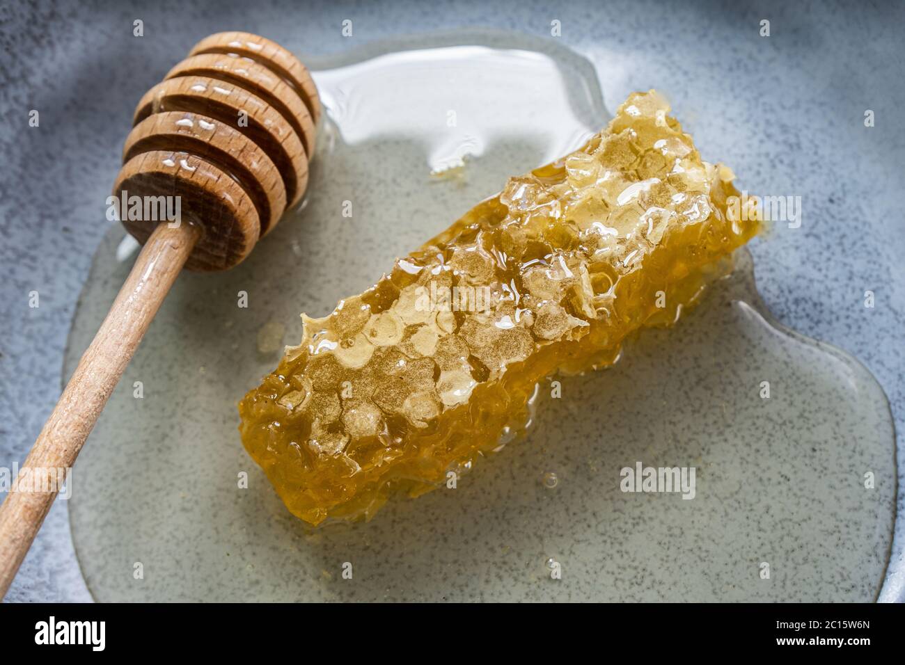 Nid d'abeille avec cuillère à miel sur assiette bleue. Banque D'Images