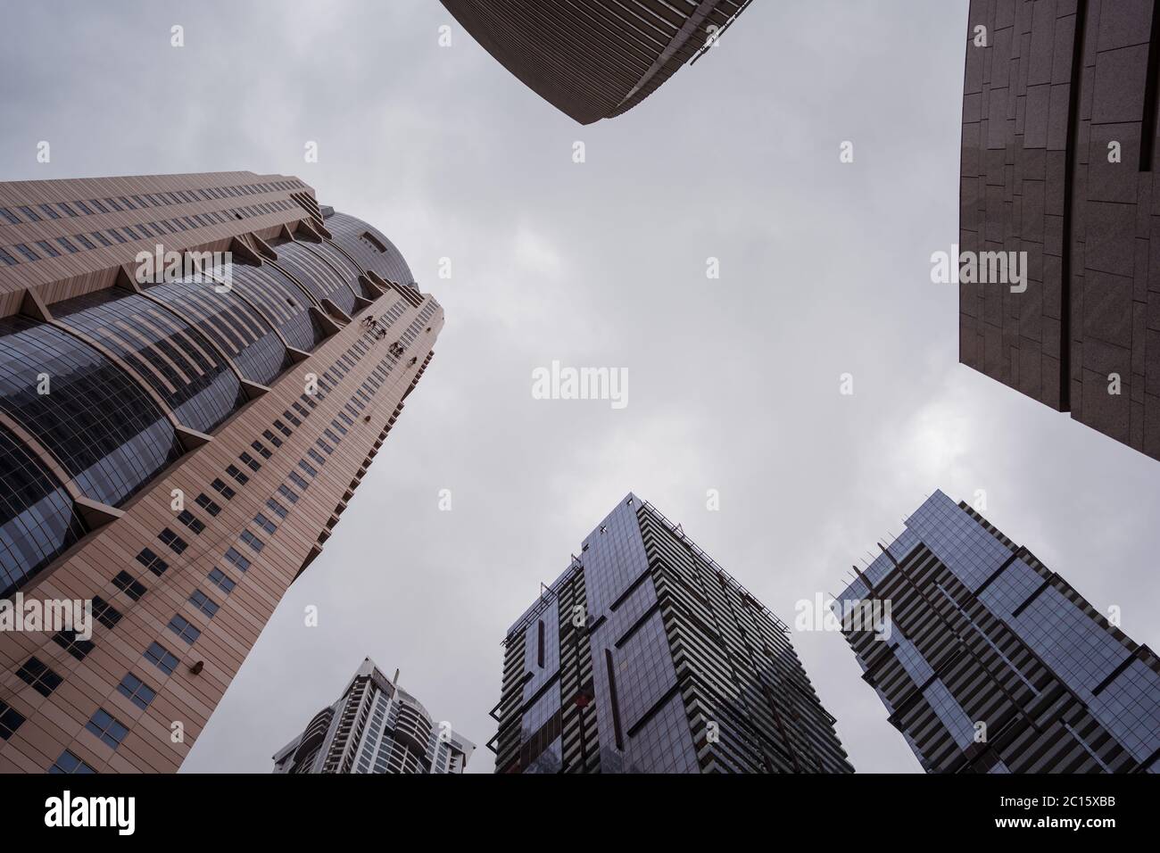 Groupe d'hommes accrochant très haut tout en nettoyant les fenêtres de gratte-ciel à Dubaï, Émirats arabes Unis Banque D'Images