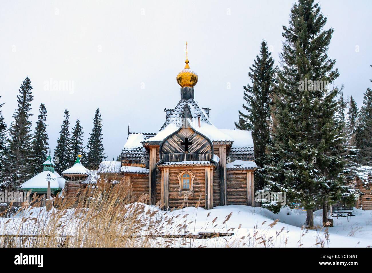 ancienne église en bois avec dôme doré et croix, maisons dans le village en hiver Banque D'Images