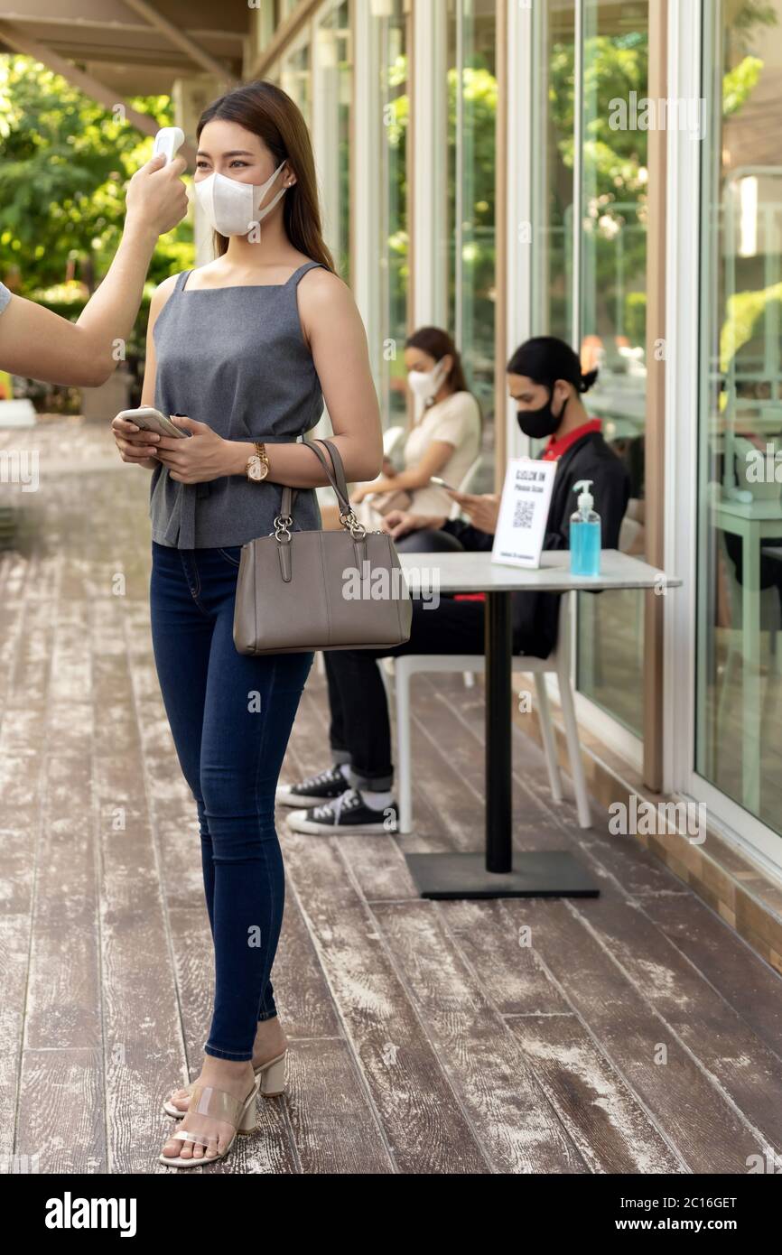 Prenez la température pour le client avec masque avant d'entrer dans le restaurant avec la file d'attente de distance sociale dans la ligne nouveau normal après le coronavirus covid-19 PAN Banque D'Images