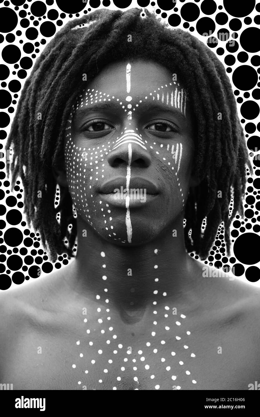 Portrait d'un jeune homme africain avec des dreadlocks et une peinture traditionnelle du visage regardant directement dans l'appareil photo Banque D'Images