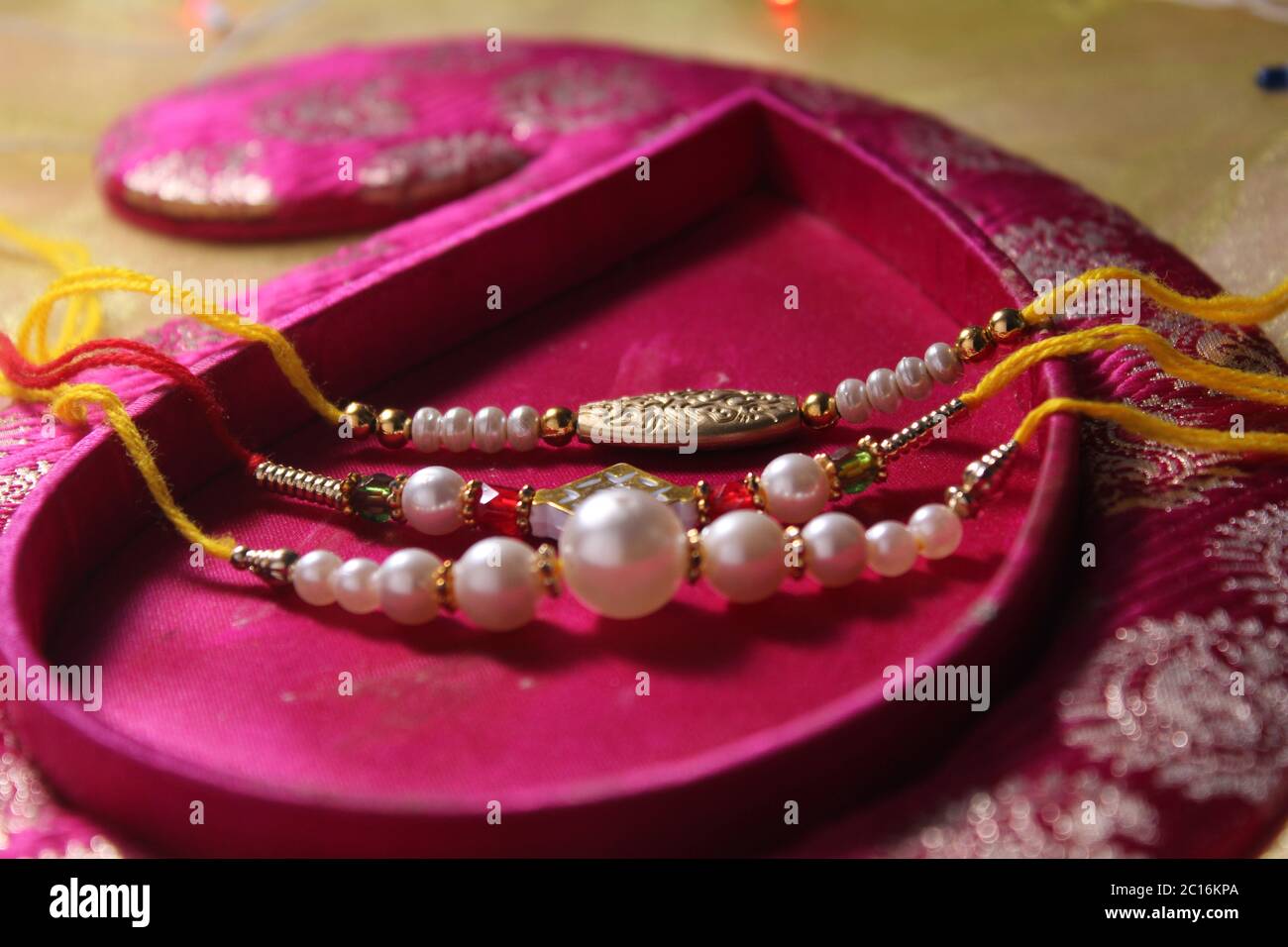 Raksha Bandhan concept de festival montrant le designer Rakhi ou Wrist Band Avec du riz et du kumkum épars, placés avec de la monnaie indienne sur coloré Banque D'Images Raksha Bandhan concept de festival montrant le designer Rakhi ou Wrist Band Avec du riz et du kumkum épars, placés avec de la monnaie indienne sur coloré Banque D'Images