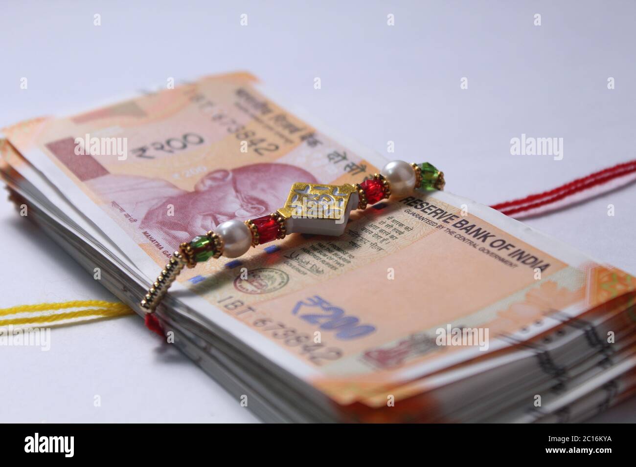 Raksha Bandhan concept de festival montrant le designer Rakhi ou Wrist Band Avec du riz et du kumkum épars, placés avec de la monnaie indienne sur coloré Banque D'Images Raksha Bandhan concept de festival montrant le designer Rakhi ou Wrist Band Avec du riz et du kumkum épars, placés avec de la monnaie indienne sur coloré Banque D'Images