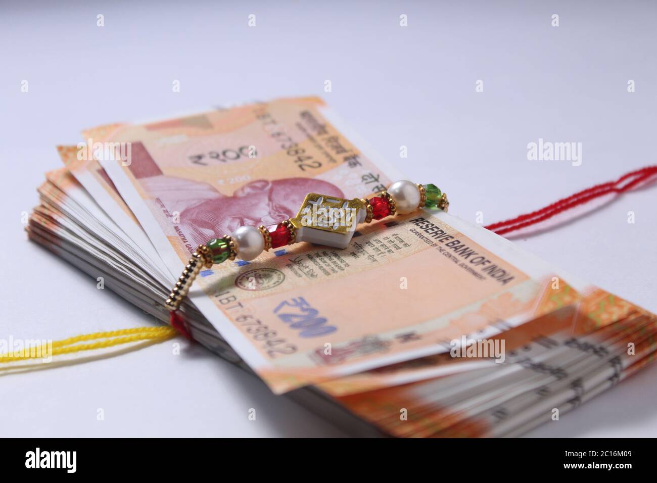 Raksha Bandhan concept de festival montrant le designer Rakhi ou Wrist Band Avec du riz et du kumkum épars, placés avec de la monnaie indienne sur coloré Banque D'Images Raksha Bandhan concept de festival montrant le designer Rakhi ou Wrist Band Avec du riz et du kumkum épars, placés avec de la monnaie indienne sur coloré Banque D'Images