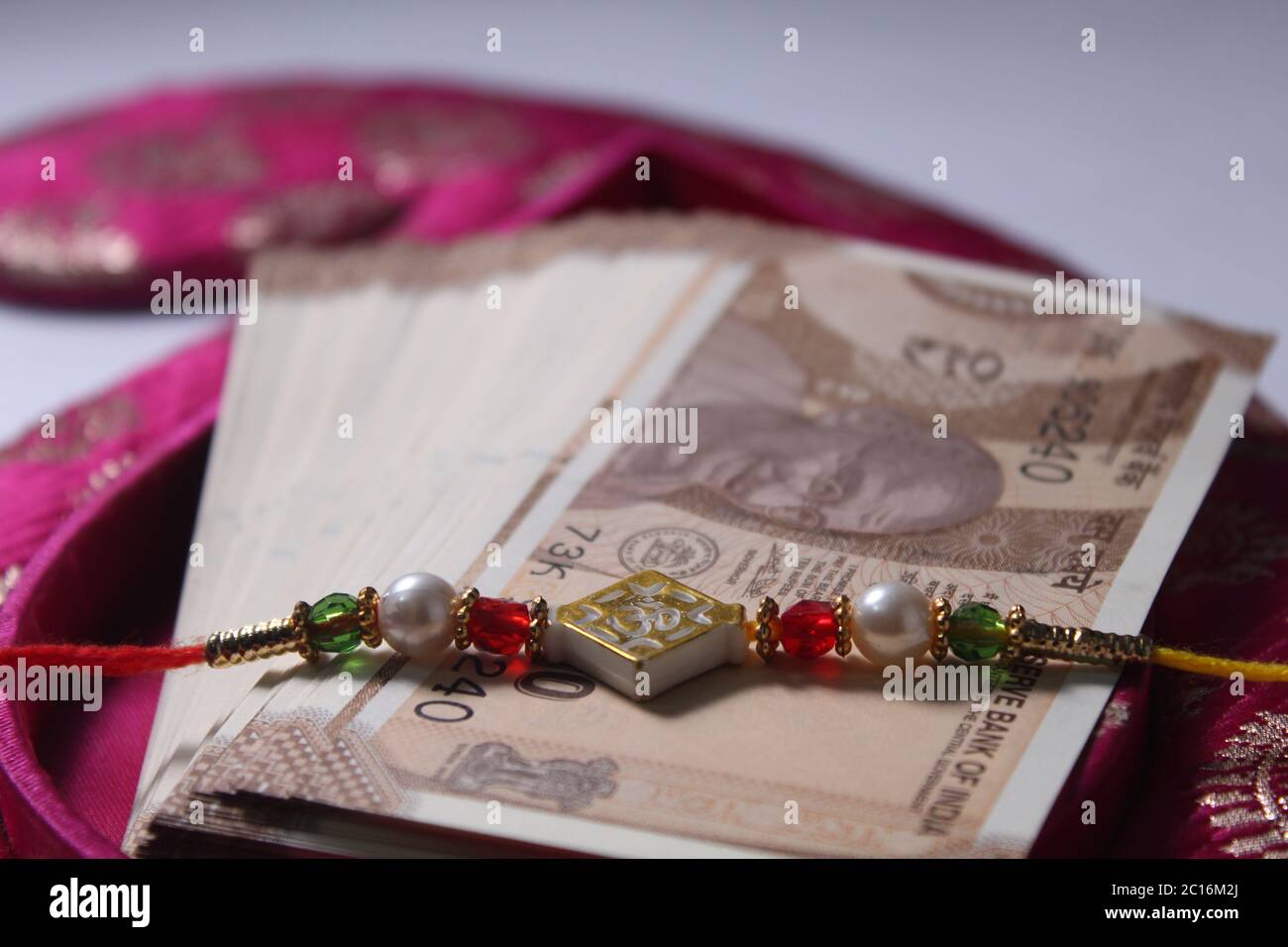 Raksha Bandhan concept de festival montrant le designer Rakhi ou Wrist Band Avec du riz et du kumkum épars, placés avec de la monnaie indienne sur coloré Banque D'Images Raksha Bandhan concept de festival montrant le designer Rakhi ou Wrist Band Avec du riz et du kumkum épars, placés avec de la monnaie indienne sur coloré Banque D'Images