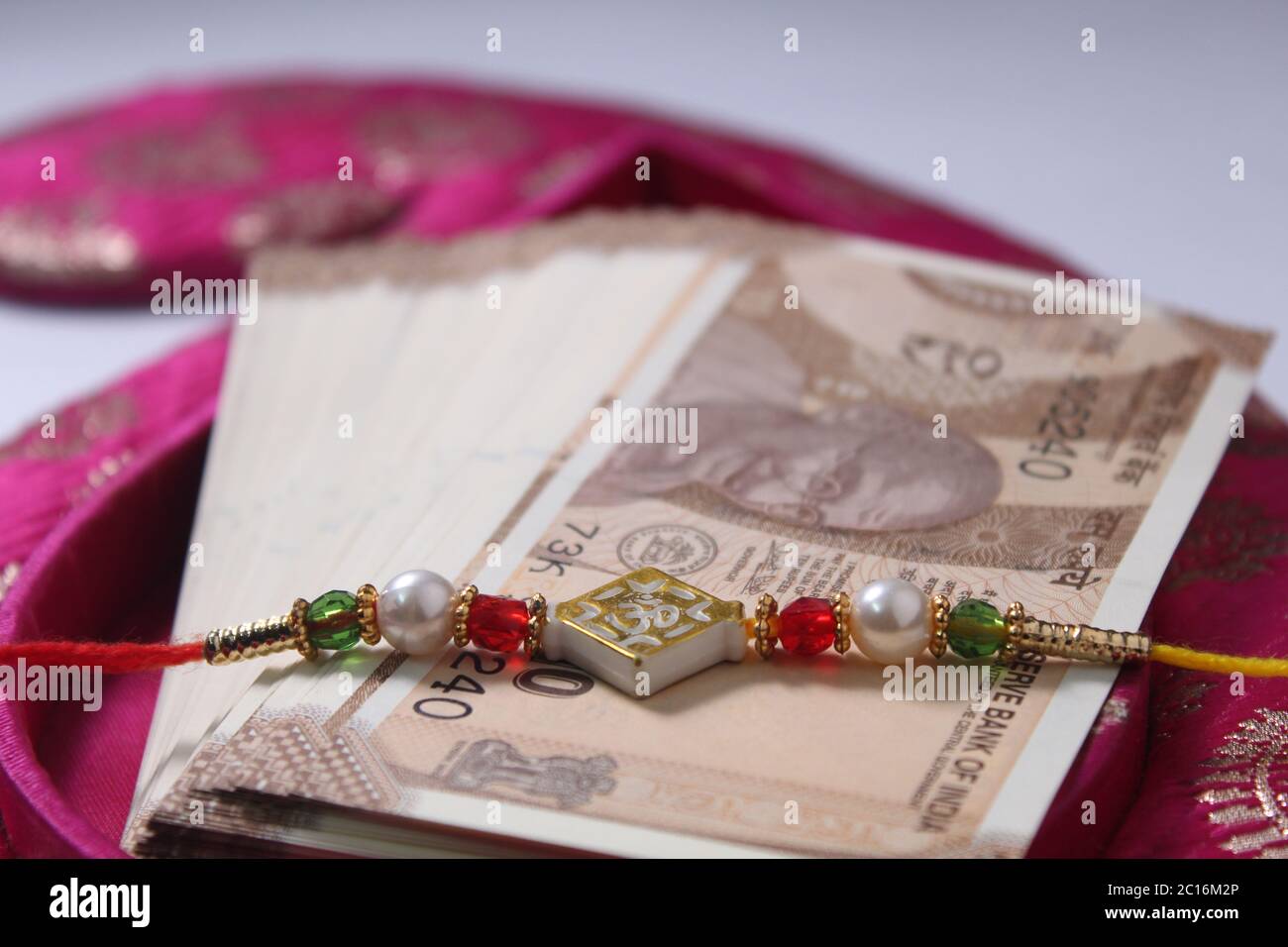 Raksha Bandhan concept de festival montrant le designer Rakhi ou Wrist Band Avec du riz et du kumkum épars, placés avec de la monnaie indienne sur coloré Banque D'Images Raksha Bandhan concept de festival montrant le designer Rakhi ou Wrist Band Avec du riz et du kumkum épars, placés avec de la monnaie indienne sur coloré Banque D'Images