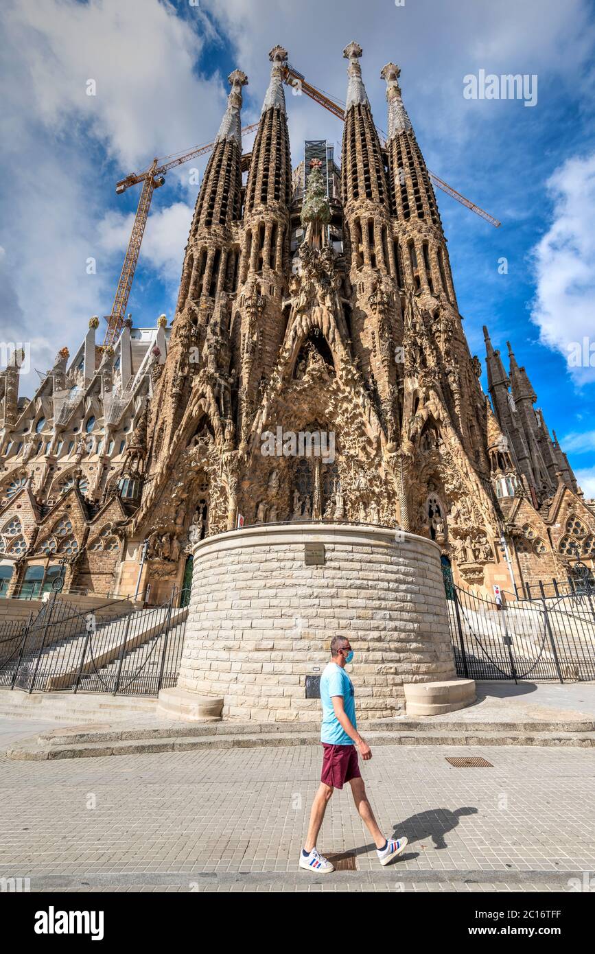 Homme adulte caucasien portant un masque chirurgical marchant devant la Sagrada Familia fermé aux visiteurs en raison de la pandémie Covid-19, Barcelone, Espagne Banque D'Images