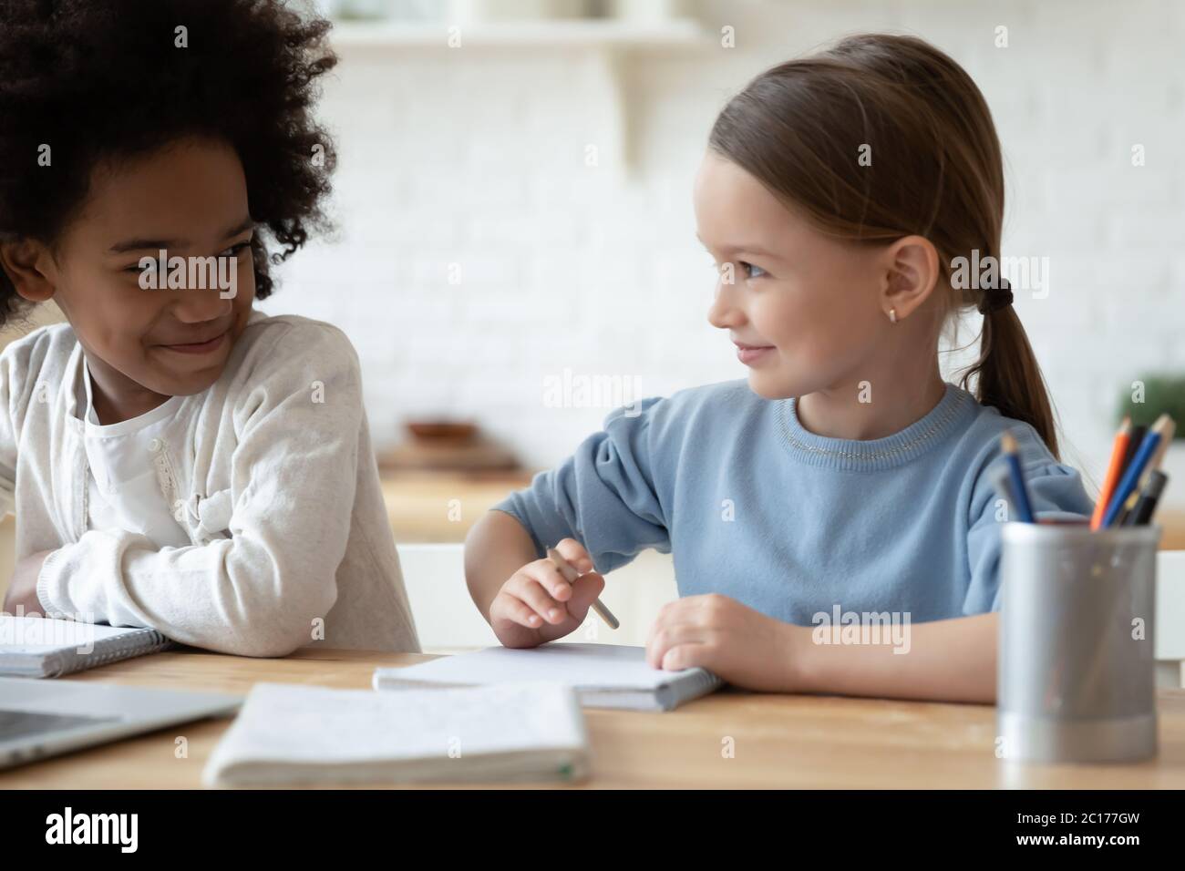 Les filles multiethniques s'assoient à table pour apprendre le sujet de l'école ensemble Banque D'Images