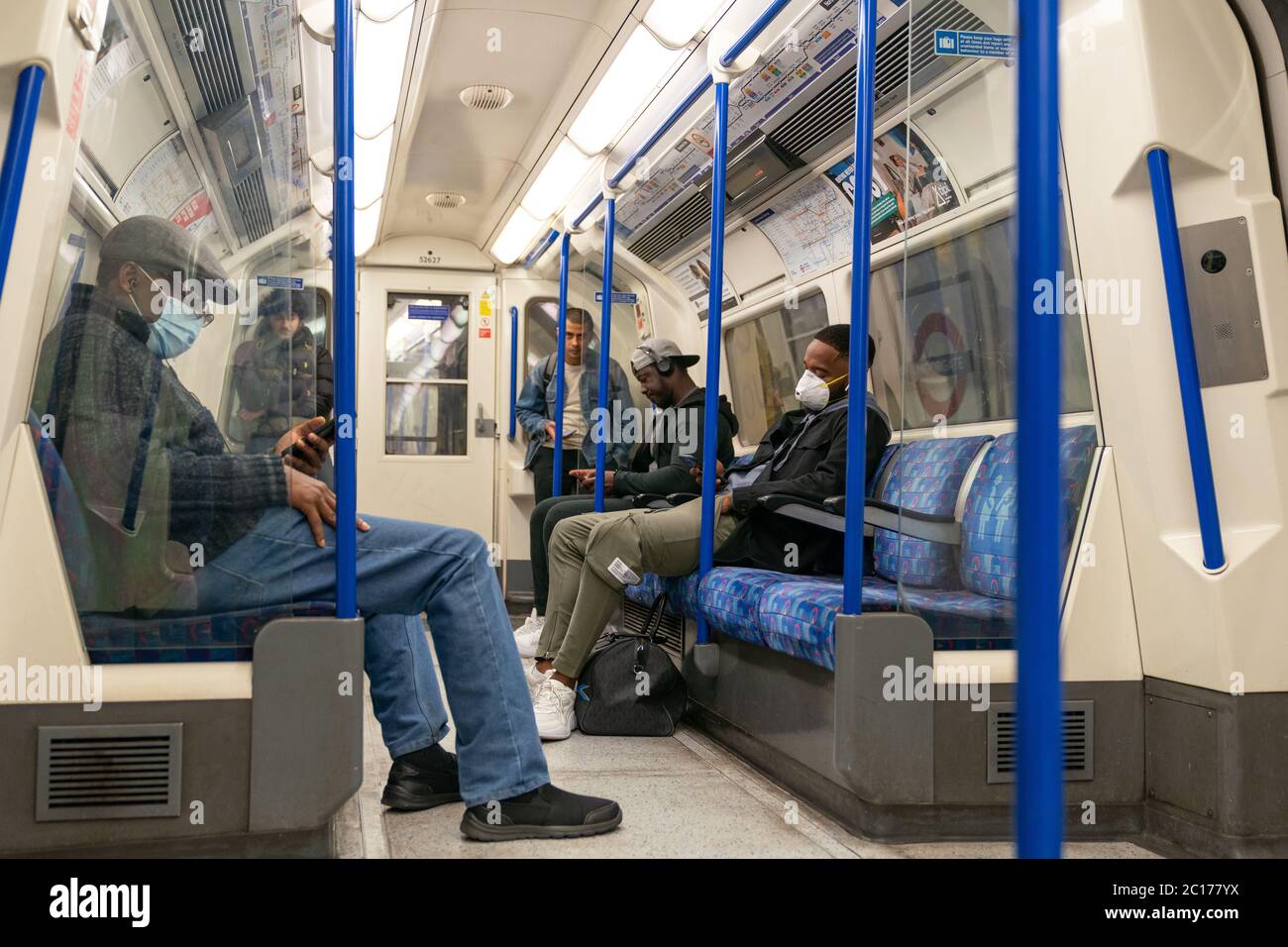 LONDRES, ANGLETERRE - 8 JUIN 2020: Groupe d'hommes sur un train de métro Piccadilly Line London portant des masques faciaux pendant le coronavirus COVID-19 1 Banque D'Images