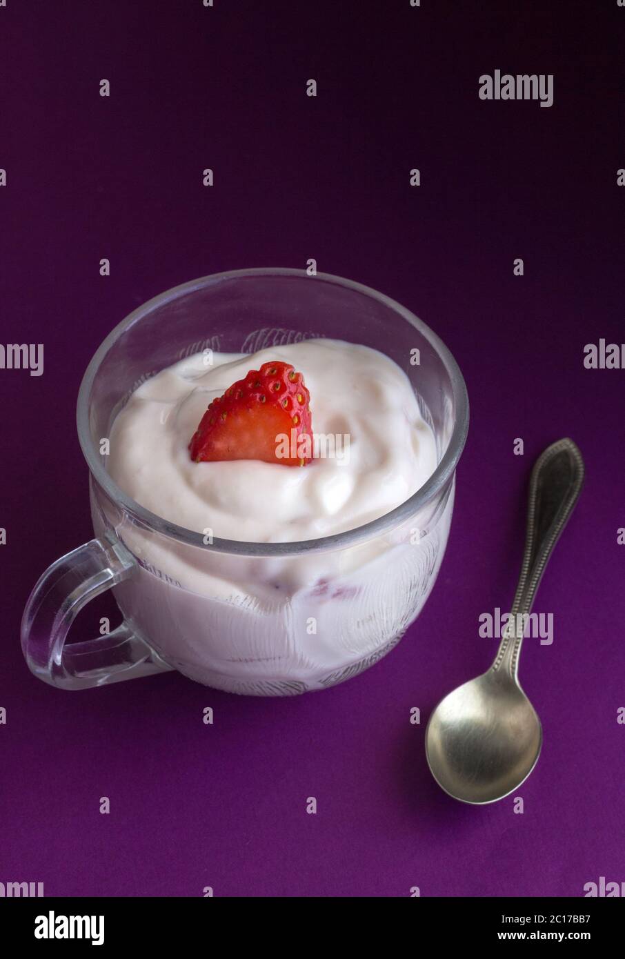 Yogourt aux fraises naturelles en petit verre tasse et cuillère à café sur fond violet close up Banque D'Images