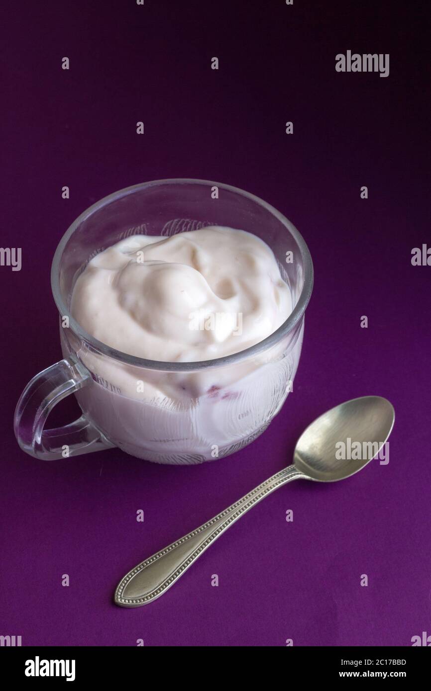 Yogourt aux fraises naturelles en petit verre tasse et cuillère à café sur fond violet close up Banque D'Images