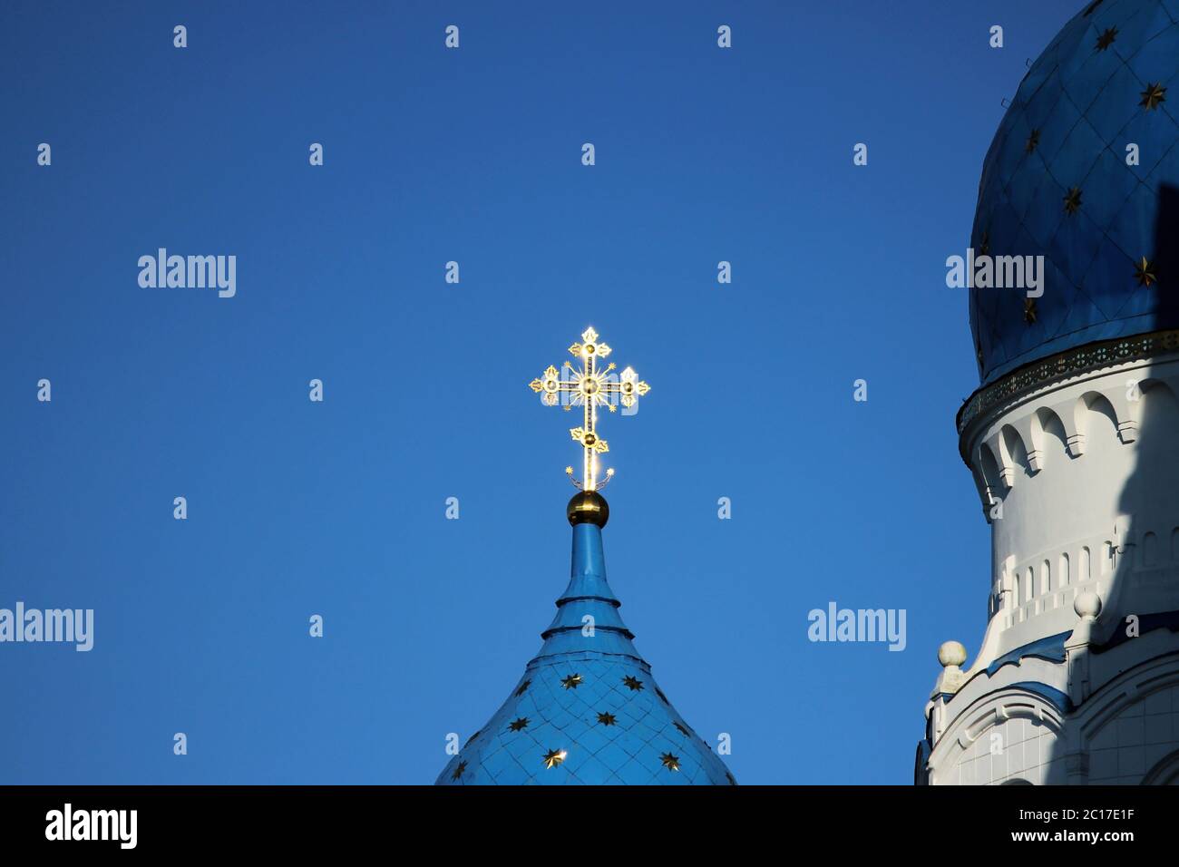 La croix dorée brille sur le dôme de l'église Cathédrale de la Sainte Vierge sur un fond bleu ciel dans la ville de Gatchina, Banque D'Images