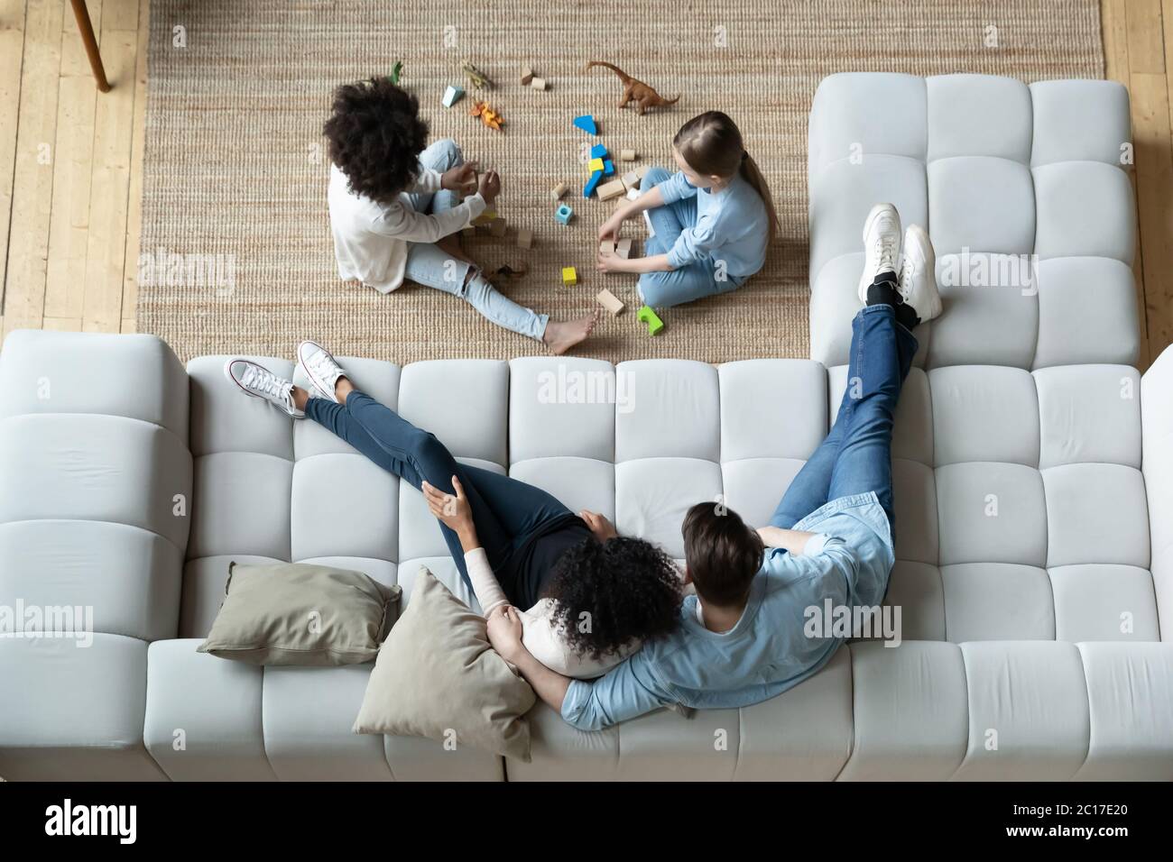 Vue ci-dessus parents reposant sur canapé filles jouer sur la moquette Banque D'Images