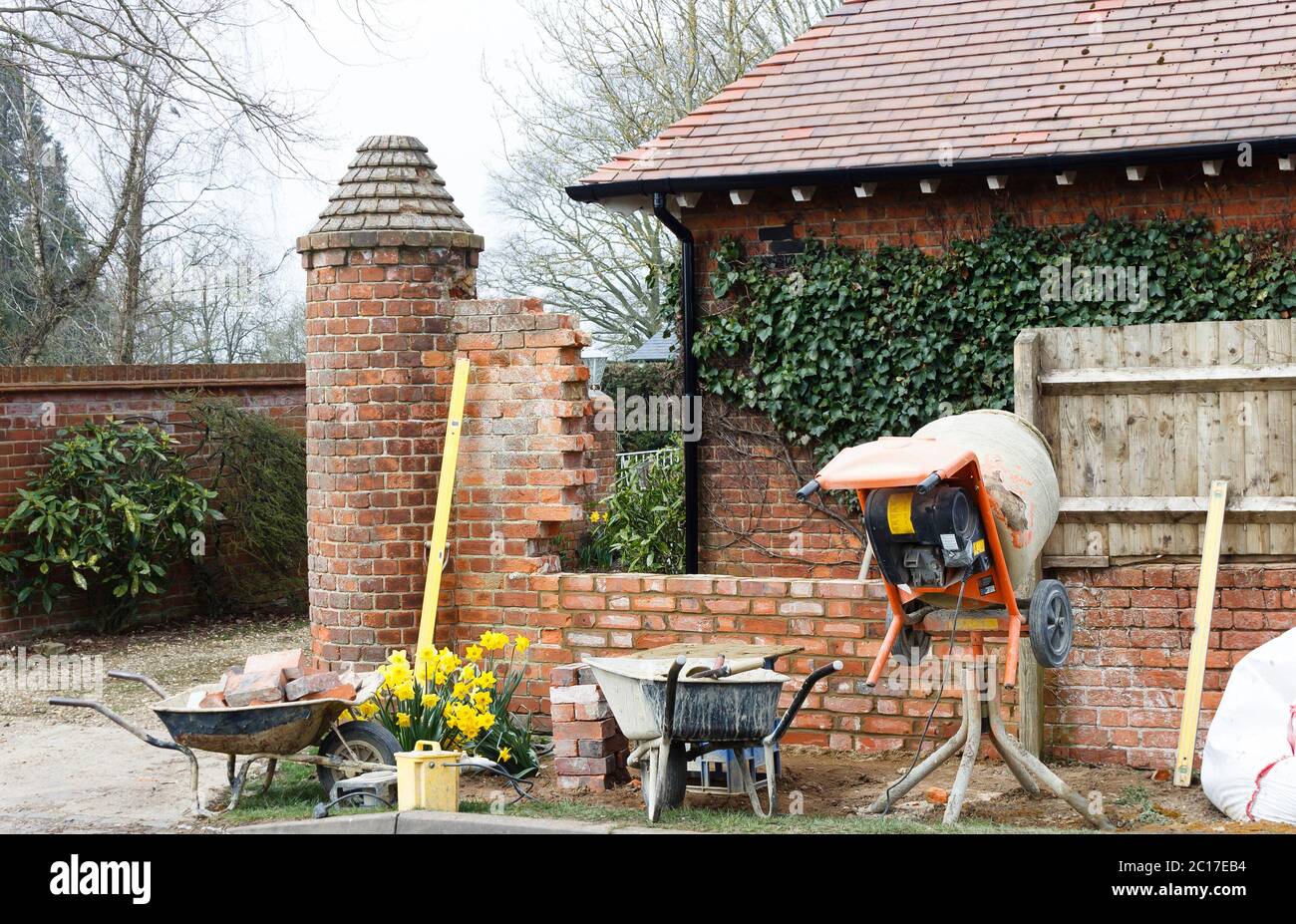 Travaux de construction avec des outils et un mélangeur de ciment, construction d'un mur de jardin en brique à l'extérieur d'une maison britannique Banque D'Images