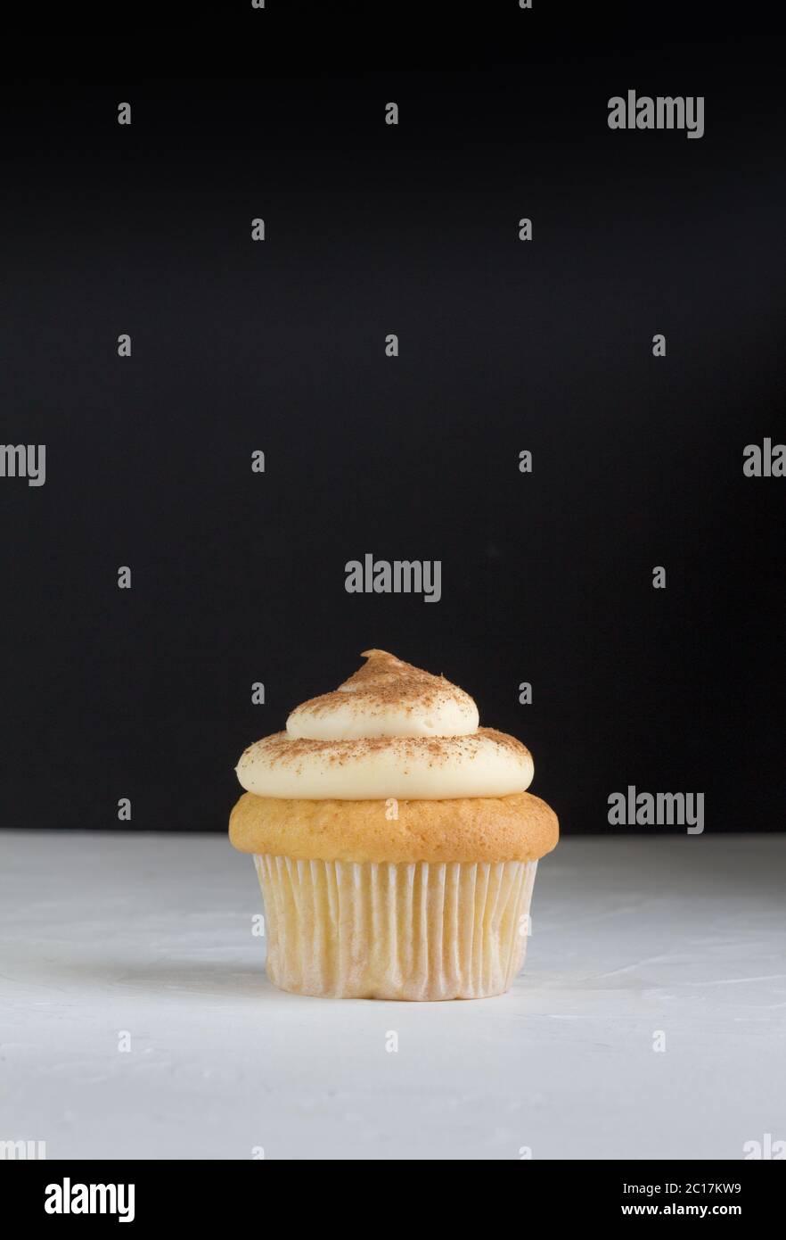 Fond de gâteau de tasse avec un cupcake sur blanc recouvert de crème à la cannelle sur blanc rustique avec d Banque D'Images