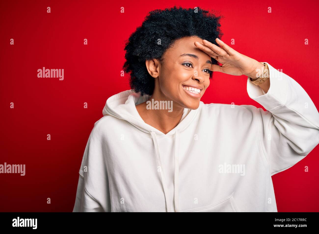 Jeune afro-américain magnifique afro sportswoman avec cheveux bouclés portant des vêtements de sport très heureux et souriant regardant loin avec la main sur la tête. Saisir Banque D'Images