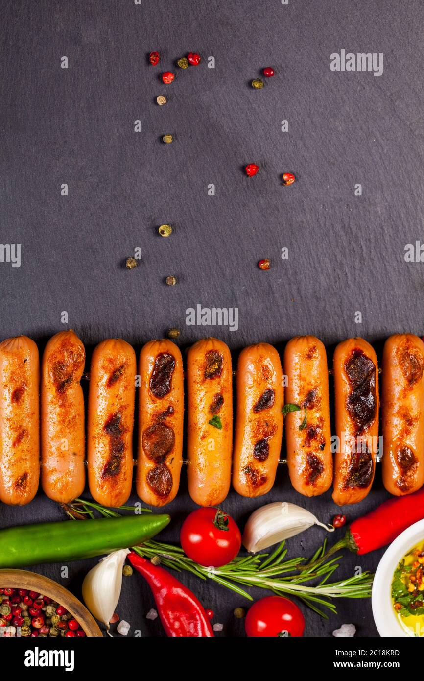 Saucisses frites aux herbes, épices et légumes sur fond noir Banque D'Images