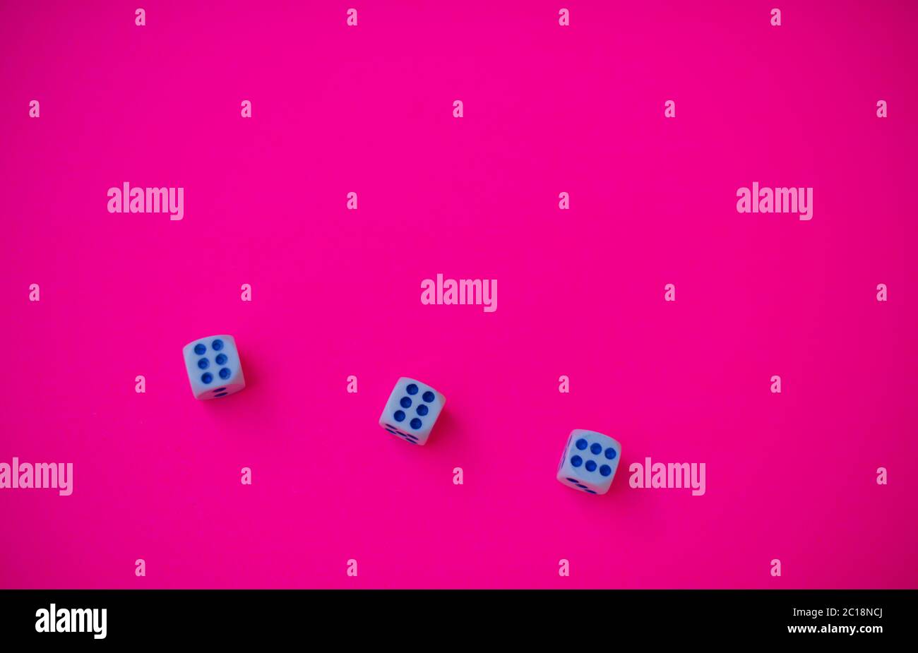 Trois dés avec le numéro six isolé sur fond rose Banque D'Images