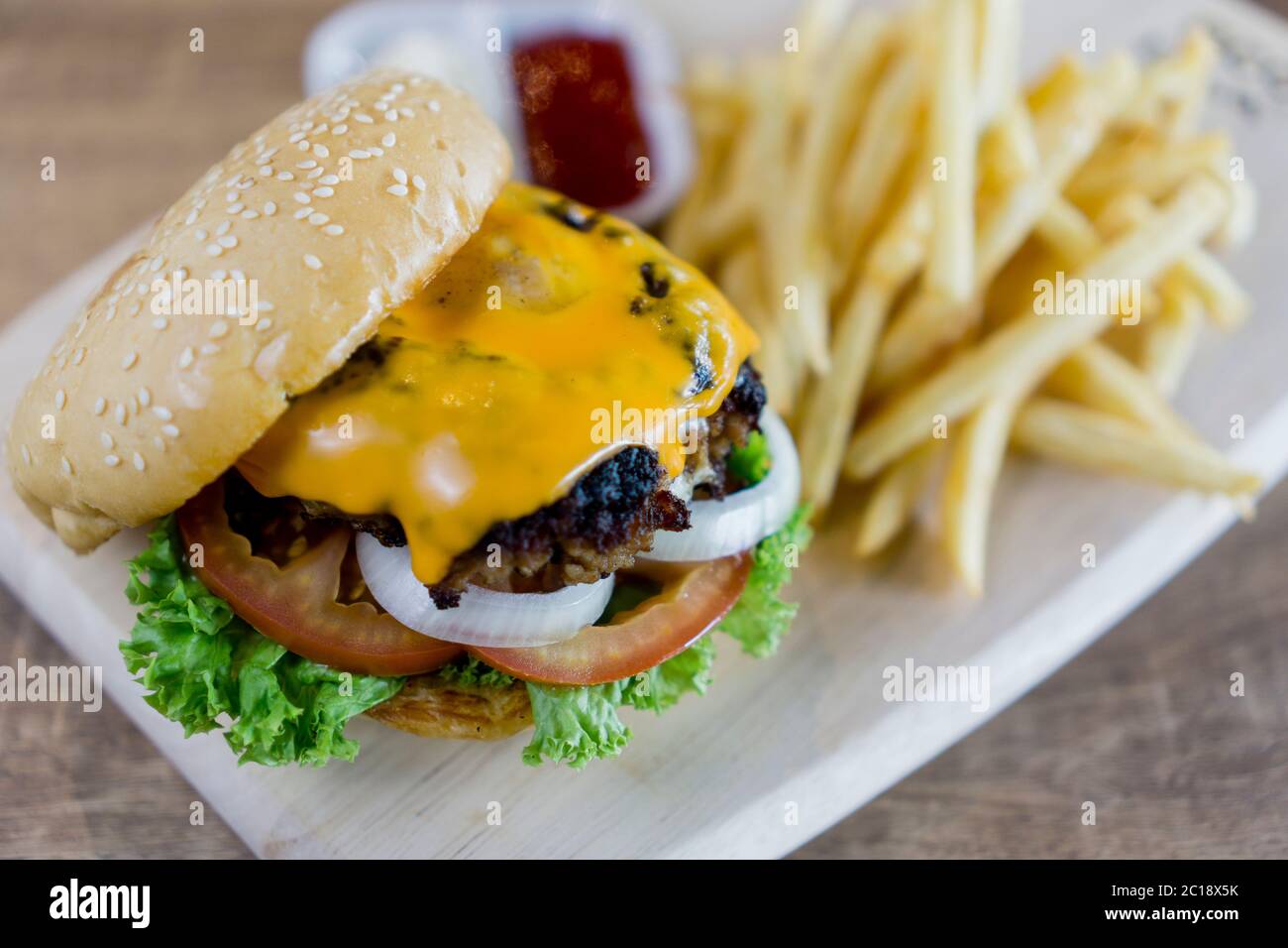 Hamburger maison avec du bœuf, de l'oignon, de la tomate, de la laitue et du fromage. Hamburger frais en gros plan avec frites et condiments. Banque D'Images