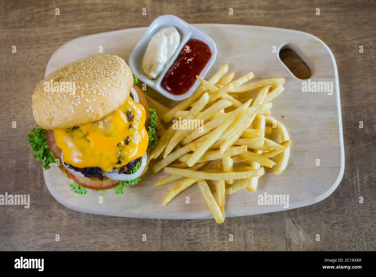 Hamburger maison avec du bœuf, de l'oignon, de la tomate, de la laitue et du fromage. Hamburger frais en gros plan avec frites et condiments. Banque D'Images