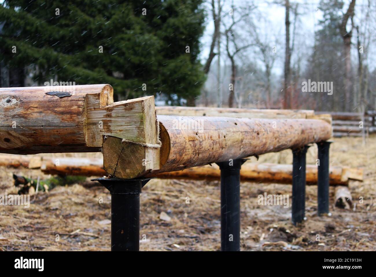 Assemblage d'un cadre en bois et construction d'une maison. Russie. Texture de vieilles billes de bois et base en colonne métallique Banque D'Images