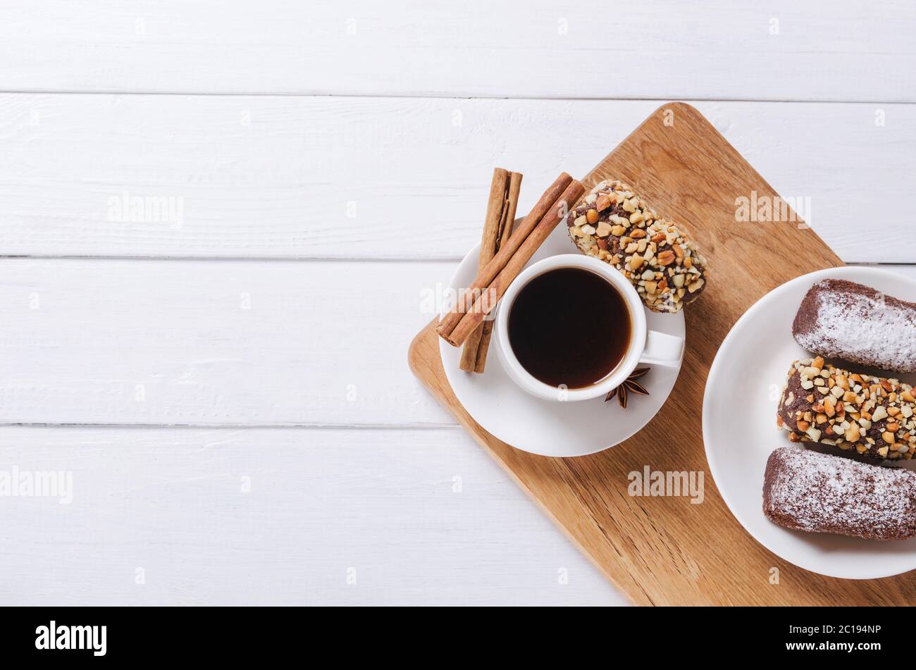 Tasse de café noire avec anis, cinnamnon et bonbons au chocolat sur fond de bois. Pose à plat Banque D'Images