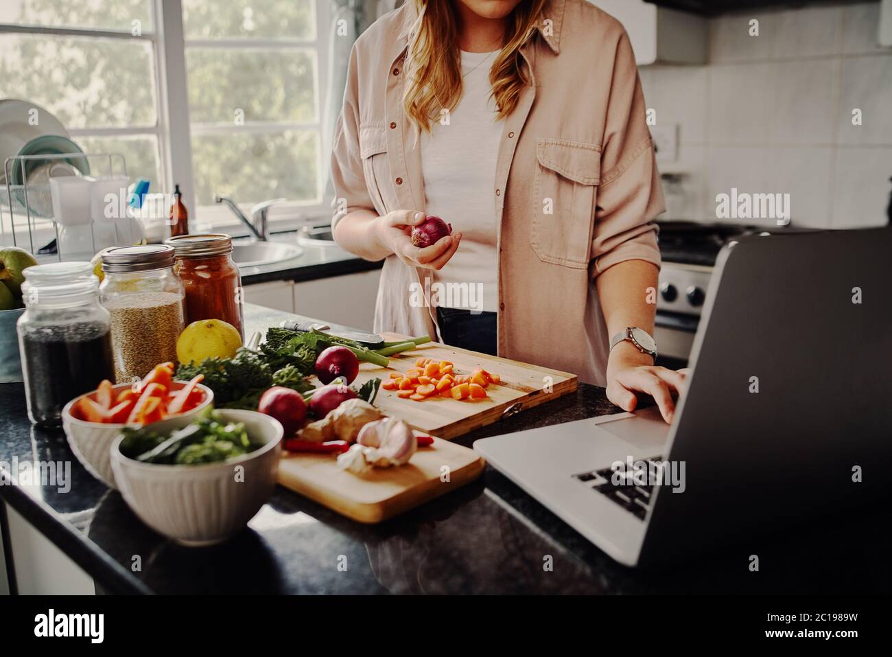 Jeune femme blogger recherche en ligne de navigation pour des recettes de préparer la salade de légumes frais et de poster sur les médias sociaux dans vlog - nouveau passe-temps pendant Banque D'Images