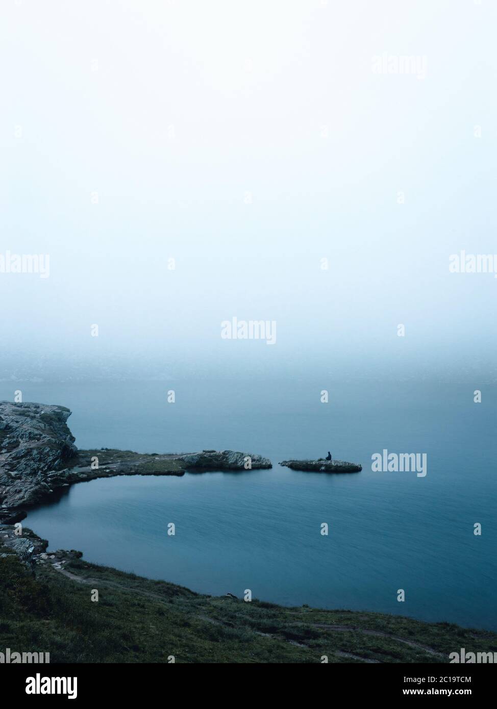 Voyageur homme debout sur isle rock, vue de brouillard minimaliste. Banque D'Images