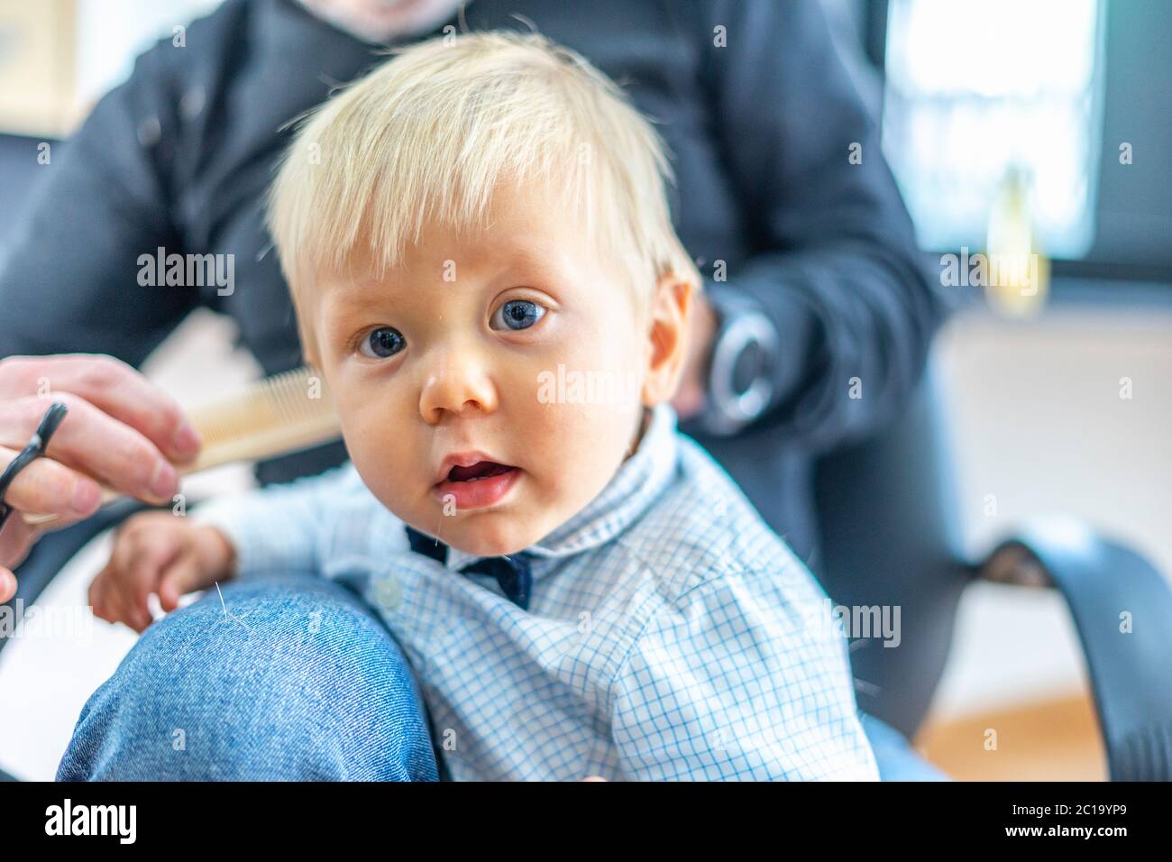 Bébé garçon blond avec les yeux bleus au salon de coiffure Banque D'Images