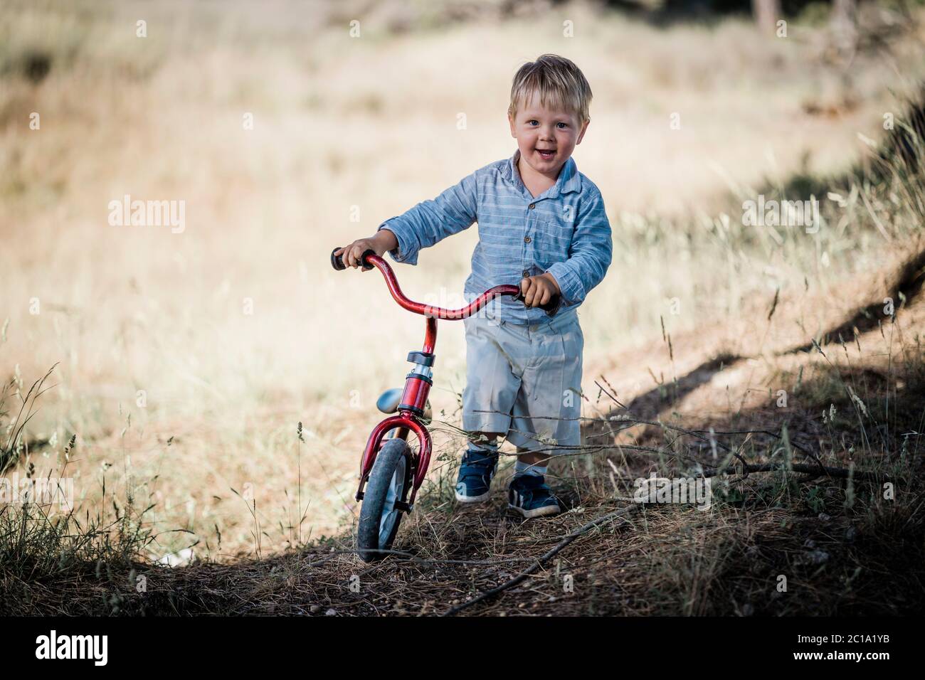 Un enfant heureux avec un petit vélo dans la nature Banque D'Images