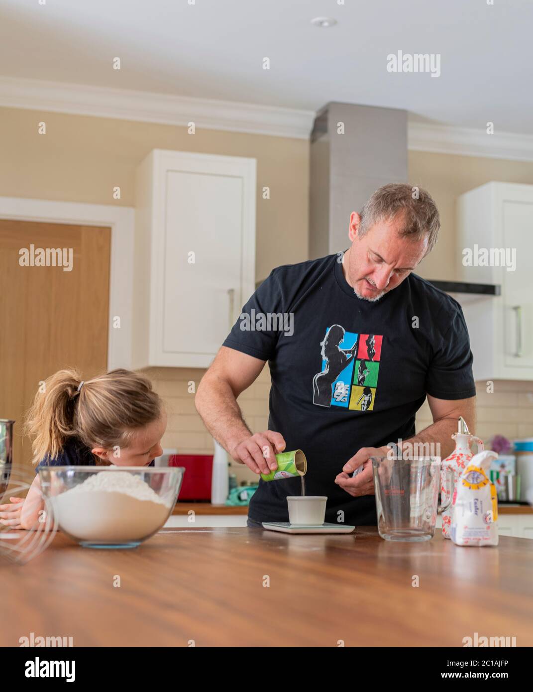 Papa et fille font de la pâte à pizza fraîche dans le batteur de cuisine. Corona Lockdown cuisine. Préparation de pizza avec Daddy pendant le verrouillage. Banque D'Images