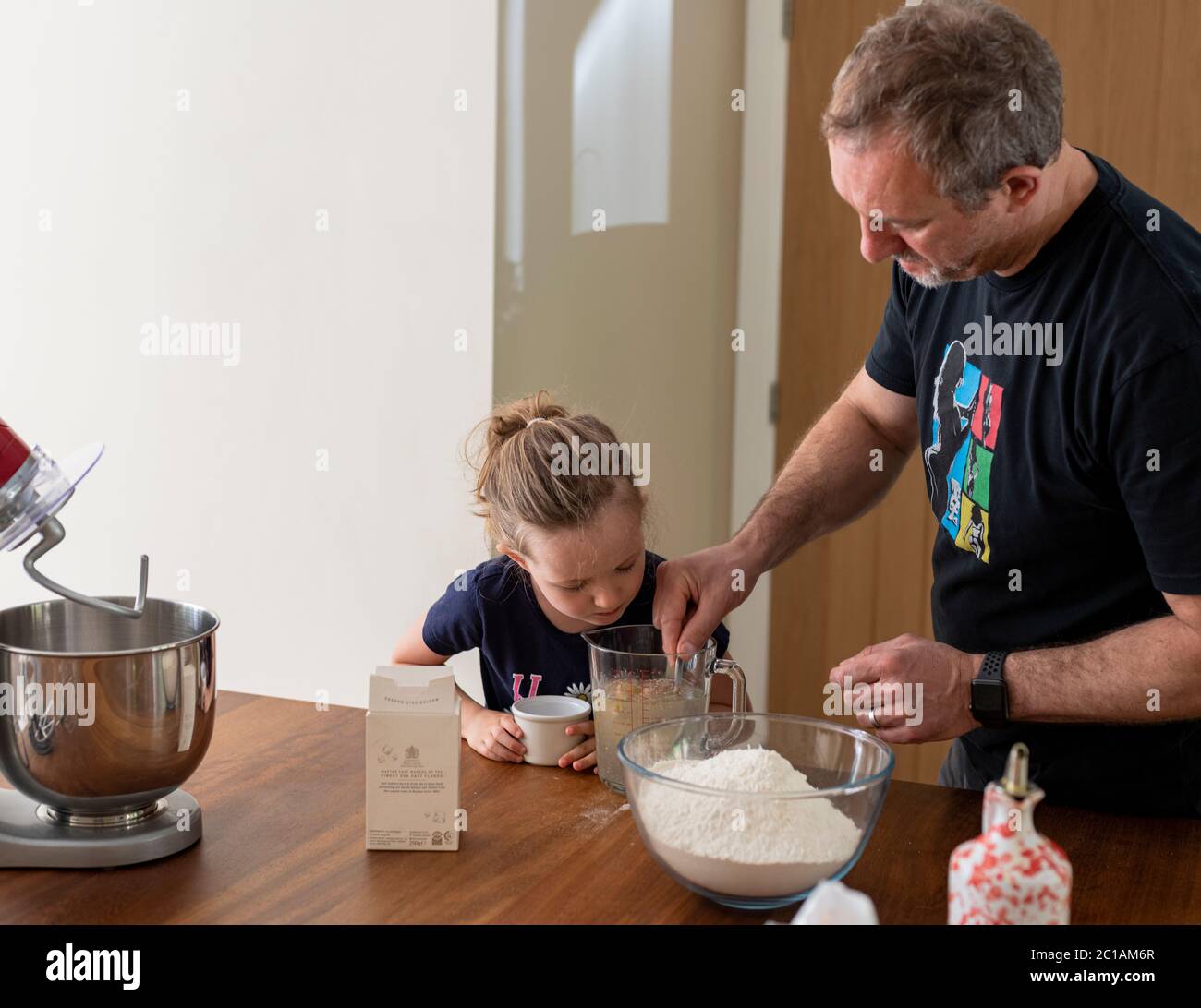 Papa et fille font de la pâte à pizza fraîche dans le batteur de cuisine. Corona Lockdown cuisine. Préparation de pizza avec Daddy pendant le verrouillage. Banque D'Images