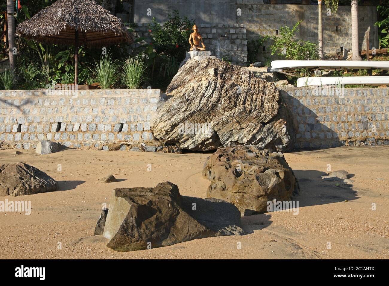 Vue sur la lapa au toit de feuilles de palmier et la statue en bois sur 293 sur Komba Guest House depuis la plage, le village d'Ampangorinana, l'île de Nosy Komba, Madagascar. Banque D'Images