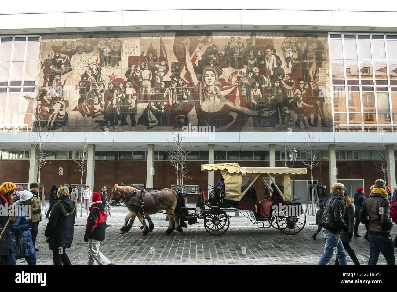 DRESDE, ALLEMAGNE - 8 DÉCEMBRE 2012 : un péroniste conduit par des chevaux et passant dans une rue pleine de touristes devant une mosaïque murale de propagande communiste DDR sur t Banque D'Images