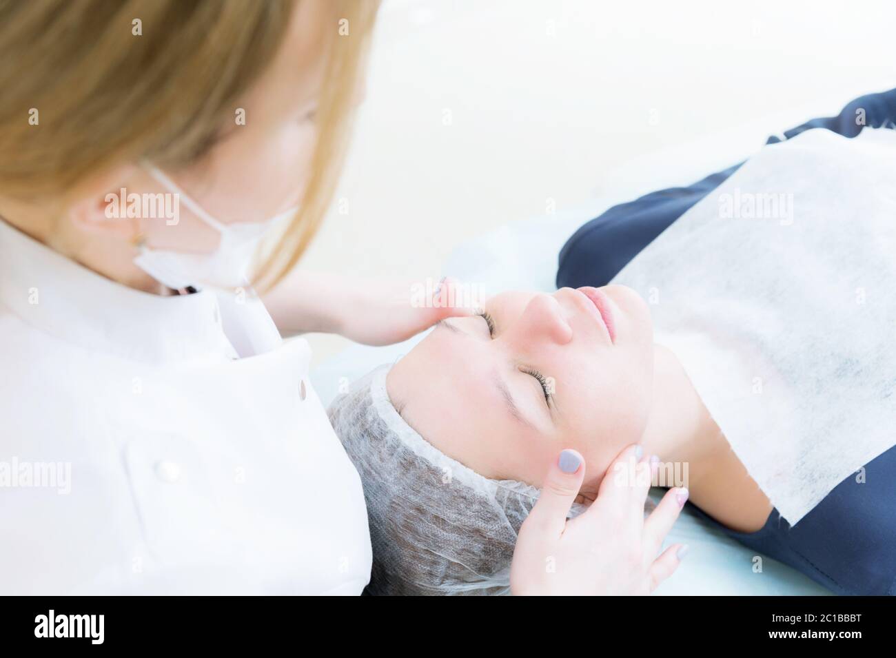 Salon de beauté. Gros plan d'une esthéticienne médicale en gants roses fait un massage du visage d'une belle femme. Cosmétologie. Tête et Banque D'Images