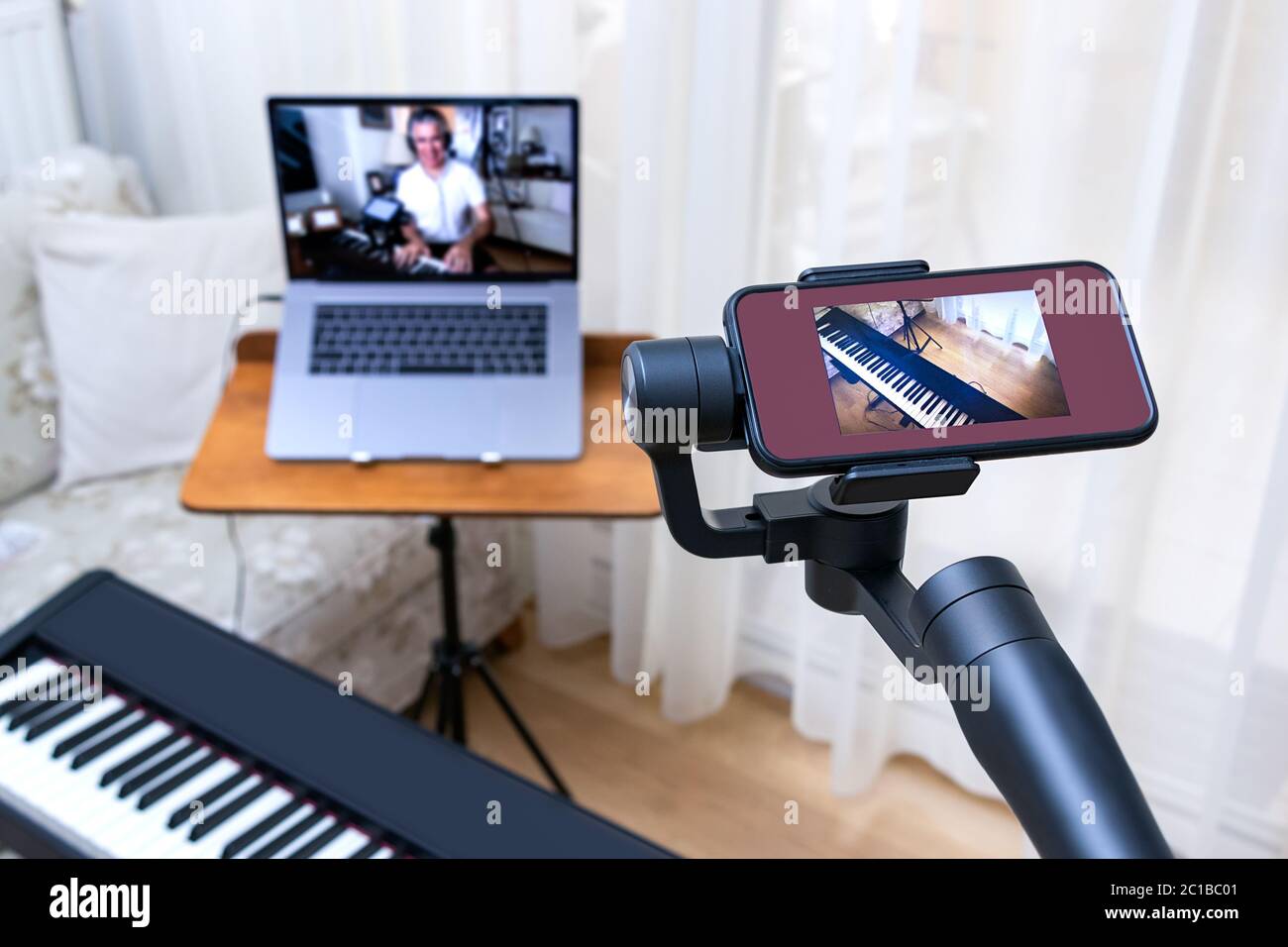Un smartphone placé sur une nacelle utilisée comme deuxième caméra pour les cours de piano en ligne. Banque D'Images