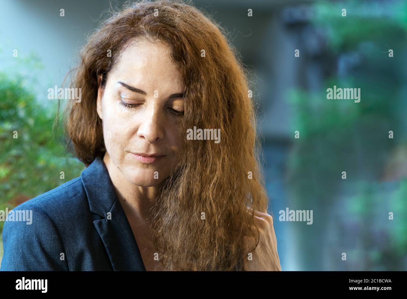 Portrait d'une femme mûre confiante regardant vers le bas avec ses yeux, rêvant, pensant, dehors Banque D'Images