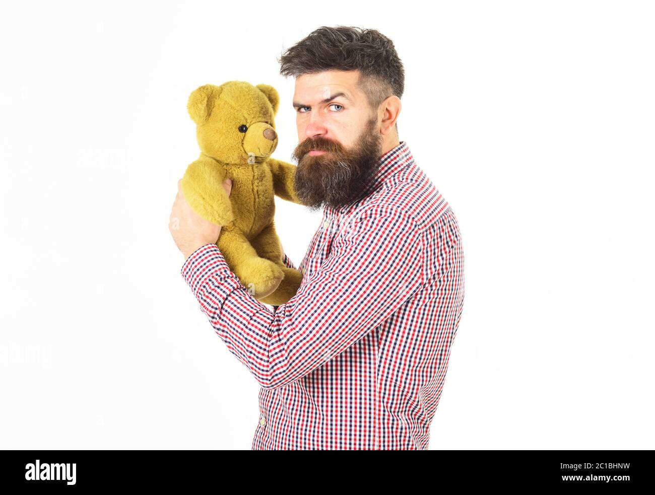 Un gars à barbe n'aime pas partager son jouet doux. Homme avec le visage strict tient l'ours en peluche ou le jouet en peluche, isolé sur fond blanc, espace de copie. Concept de la saludesse. Il tient son jouet dans une hipster misérable. Banque D'Images