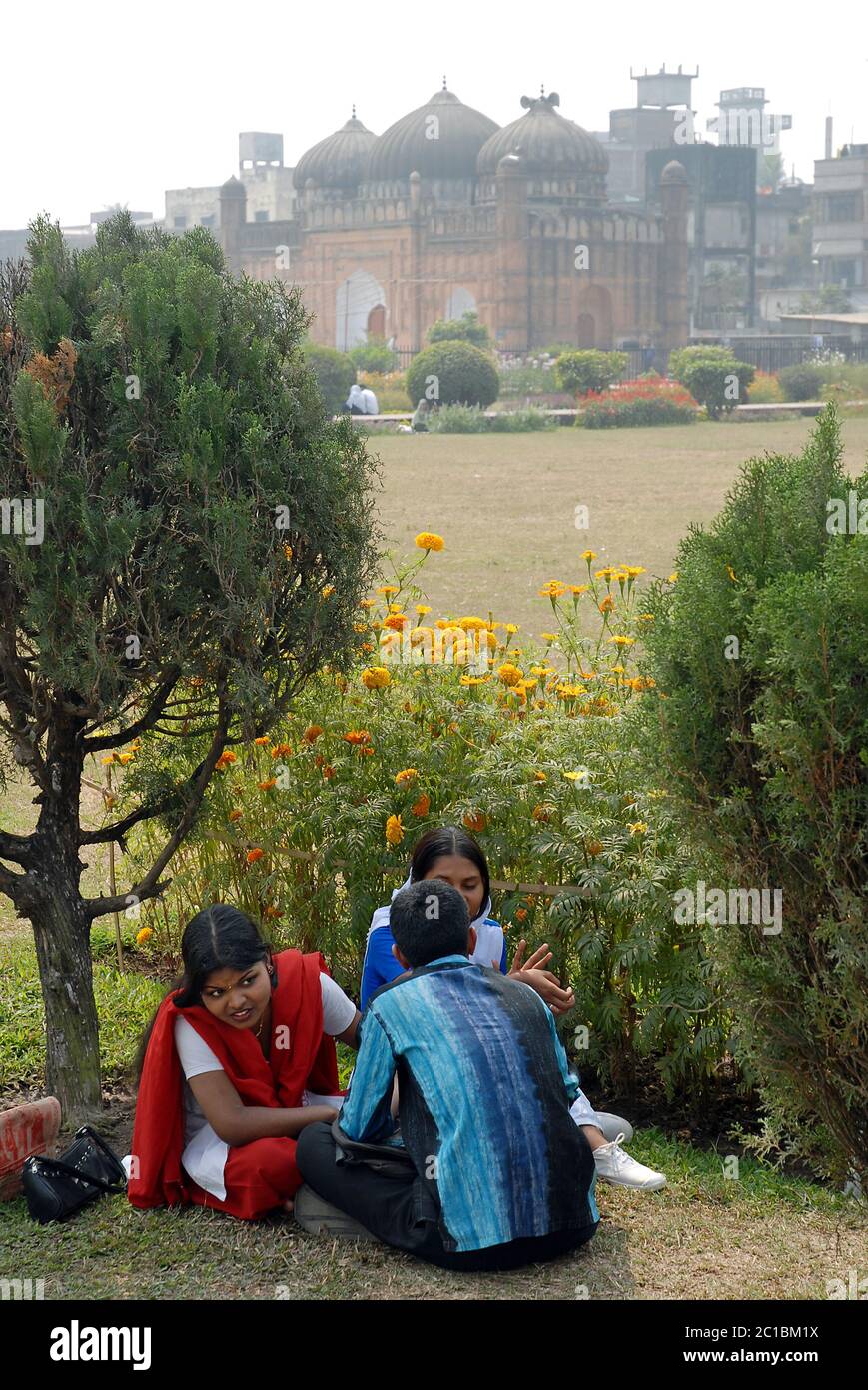 Les habitants de la région s'assoient et parlent dans le domaine du fort de Lalbagh, à Dhaka. Derrière eux se trouve la mosquée à trois dômes du fort de Lalbagh. Vue touristique Dhaka, Bangladesh. Banque D'Images