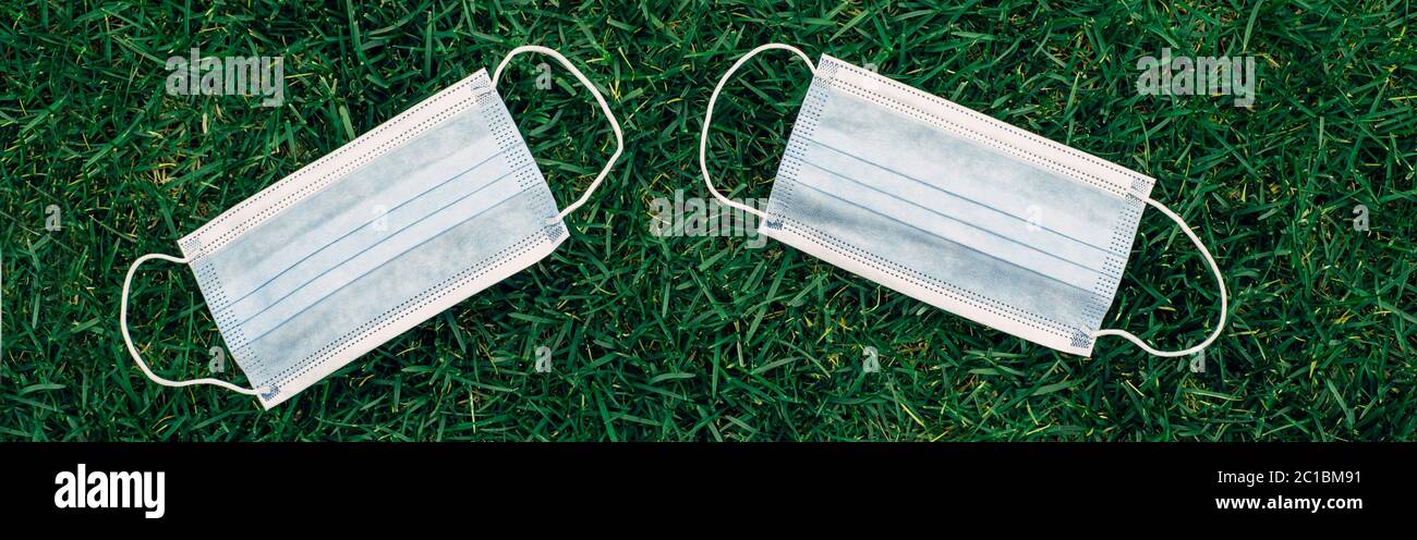Deux nouveaux masques sanitaires frais posés sur l'herbe. Masque jetable recyclable plat. Coronavirus, médecine et allergie saisonnière concept. Banque D'Images